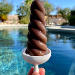 Sip chocolate popsicle with pool in background